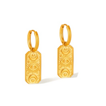 Boucles d'Oreilles Abydos - mini créoles dorées pendentif rectangulaire œil protecteur et astres gravés présentées - LELIEGE