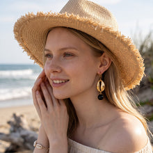 Boucles d'Oreilles Cauri - crochet doré pendentif cauri et perle d'onyx noir sur fond blanc - LELIEGE