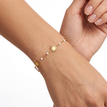 Bracelet Surya - bracelet doré, soleils et perles émaillées blanches porté au poignet - LELIEGE