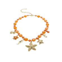Collier Bahia - perles résine orange rondes et facettées intercalaires dorés 7 charms marins sur fond blanc - LELIEGE